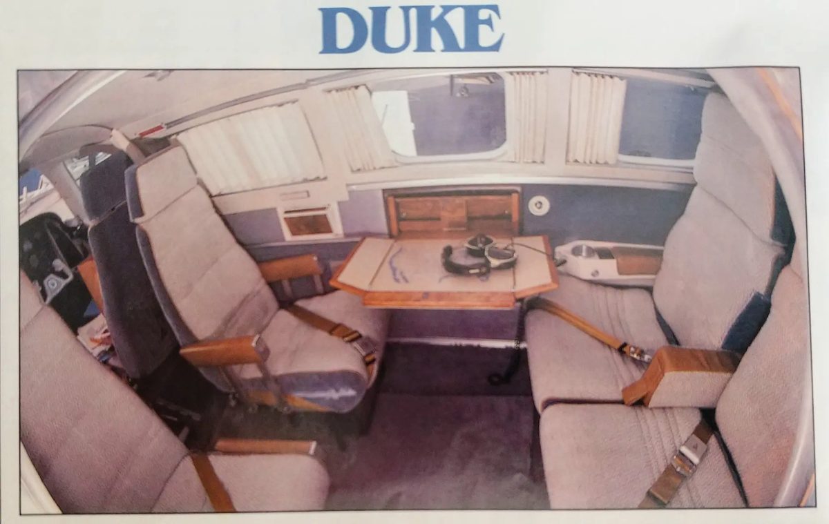 Original Duke cabin interior — club seating, fold-out table, curtains